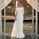 Robe de mariée civile simple en satin, manches 3/4 et col rond, coupe trapèze, ornée d'appliques en dentelle, disponible en 2025. Pas chère.