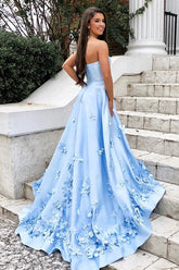 Robe de bal longue bleu ciel en satin, décolleté cœur, coupe trapèze, ornée d'appliqués floraux 3D.