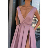 Vestido largo de fiesta rojo satinado de corte evasé, escote en V profundo, abertura alta y bolsillos.