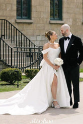 Precioso vestido de novia blanco de corte A, con hombros descubiertos, escote redondo, sin mangas, volantes y abertura frontal en satén.