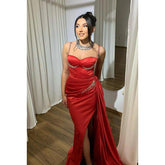 Vestido de fiesta de corte sirena con tirantes finos, abertura lateral y fruncido, con pedrería y alta costura.