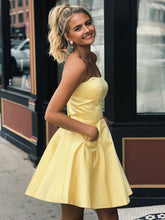 Lindos vestidos cortos de satén amarillo estilo A, sin tirantes, para baile de graduación o fiesta de bienvenida, con bolsillos.