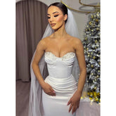 Robe de mariée longue à plis blancs et perles, décolleté en cœur