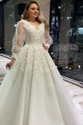 Vestido de novia largo de corte A, escote en V, apliques de encaje y tul con mangas largas abullonadas.
