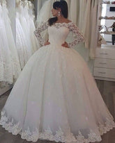 Vestido de novia princesa de manga larga con hombros descubiertos y apliques de encaje.