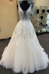 Robe de mariée unique longue en tulle et dentelle perlée, col en V, coupe trapèze.