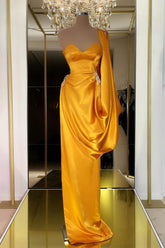 Robe de bal longue unique en or jaune, ornée de volants et asymétrique.