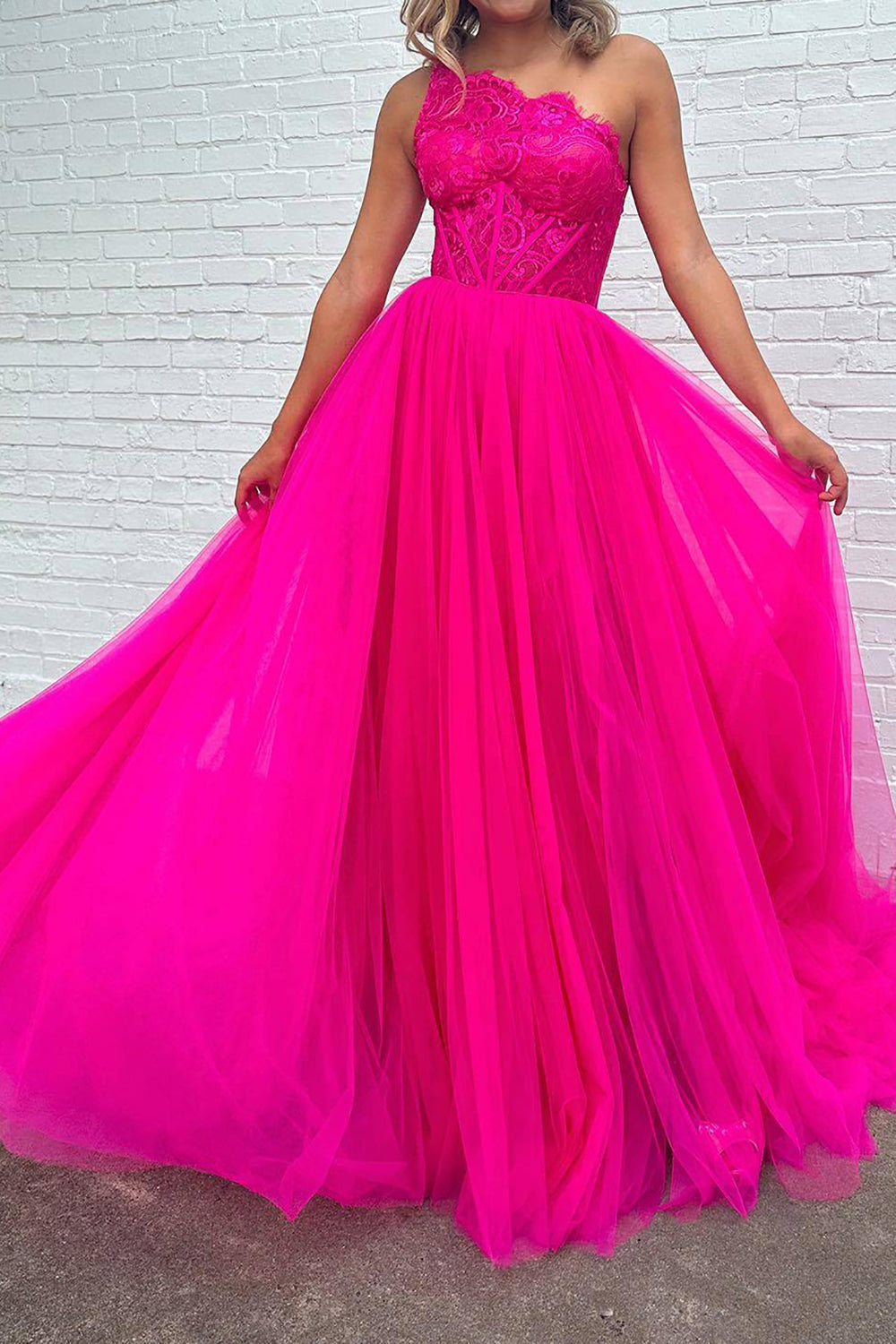 Vestido de fiesta fucsia de corte A, corte asimétrico, con corsé y abertura frontal.