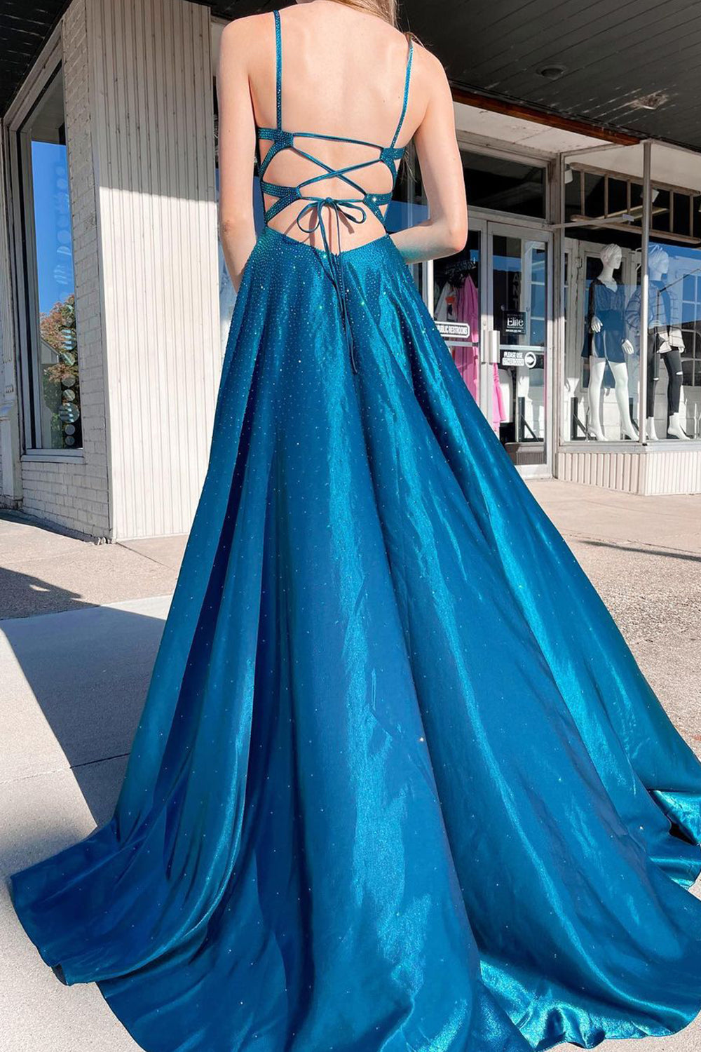 Vestido largo de fiesta azul pavo real con tirantes finos, corte en A y abertura frontal.