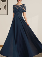 Robe de mariée longue en mousseline de soie et dentelle, coupe trapèze, décolleté illusion, ornée de sequins et de perles.