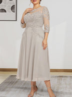Robe de mariée trapèze en mousseline de soie et dentelle, longueur thé, ornée de perles et de sequins, avec décolleté en A et effet illusion.