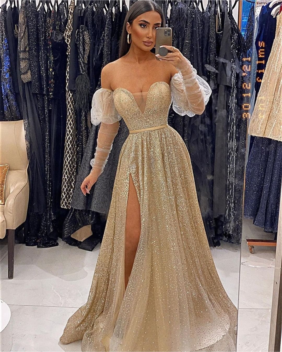 Robe de bal à manches longues et décolleté cœur, ornée de sequins et fendue.
