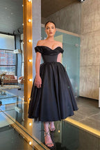 Vestido de graduación negro de corte A, elegante y deslumbrante, con hombros descubiertos y volantes.