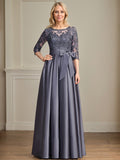 Robe de mariée longue en satin et dentelle, coupe trapèze, décolleté illusion, ornée d'un nœud à sequins. 
