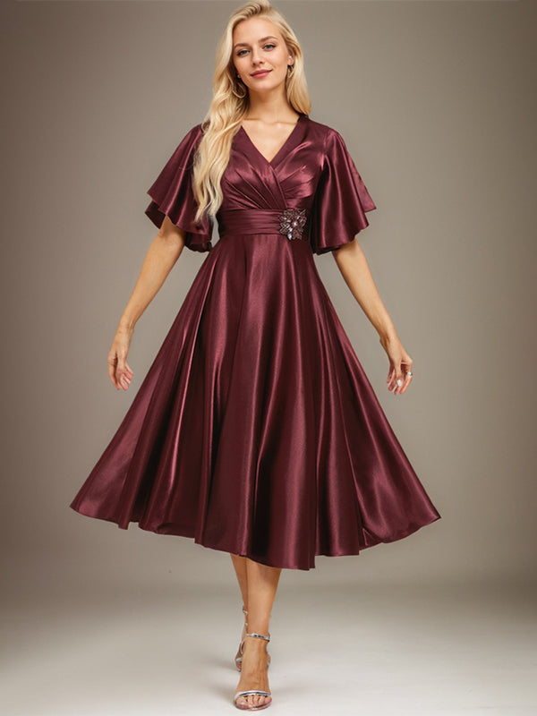 Vestido de novia de satén elástico, corte en A, escote en V, largo hasta la rodilla, con cuentas y pliegues. 
