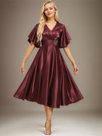 Vestido de novia de satén elástico, corte en A, escote en V, largo hasta la rodilla, con cuentas y pliegues. 