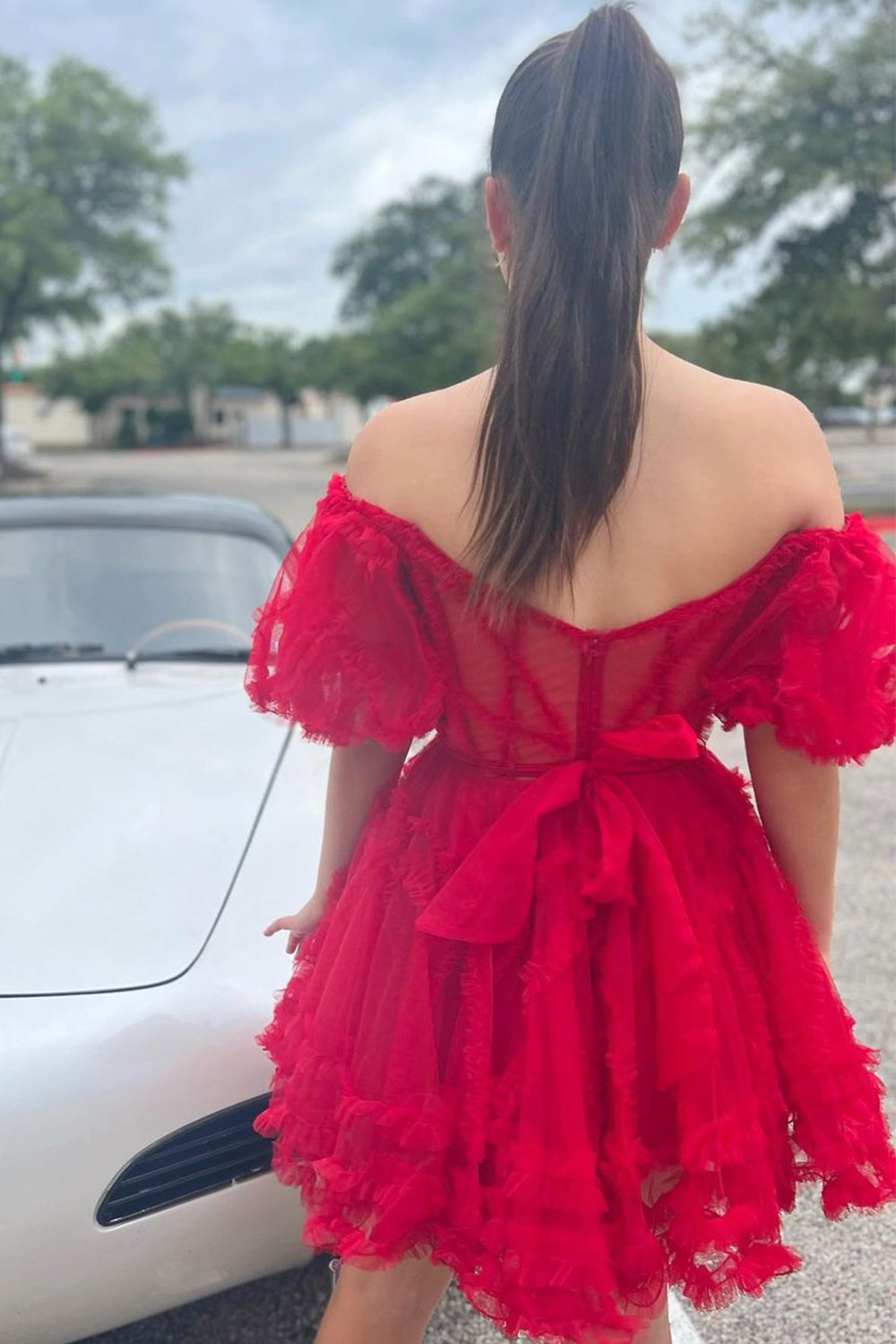 Robe de bal unique en tulle fuchsia, coupe trapèze, épaules dénudées et corset.