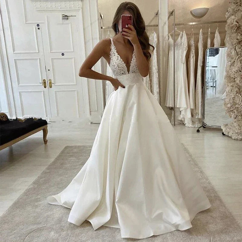 Vestido de novia blanco satinado corte A, escote en V profundo, estilo boho, con apliques sencillos, espalda descubierta y bolsillo.