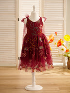 Vestido de niña pequeña hasta la rodilla, de encaje y tul color naranja quemado con bordados. 