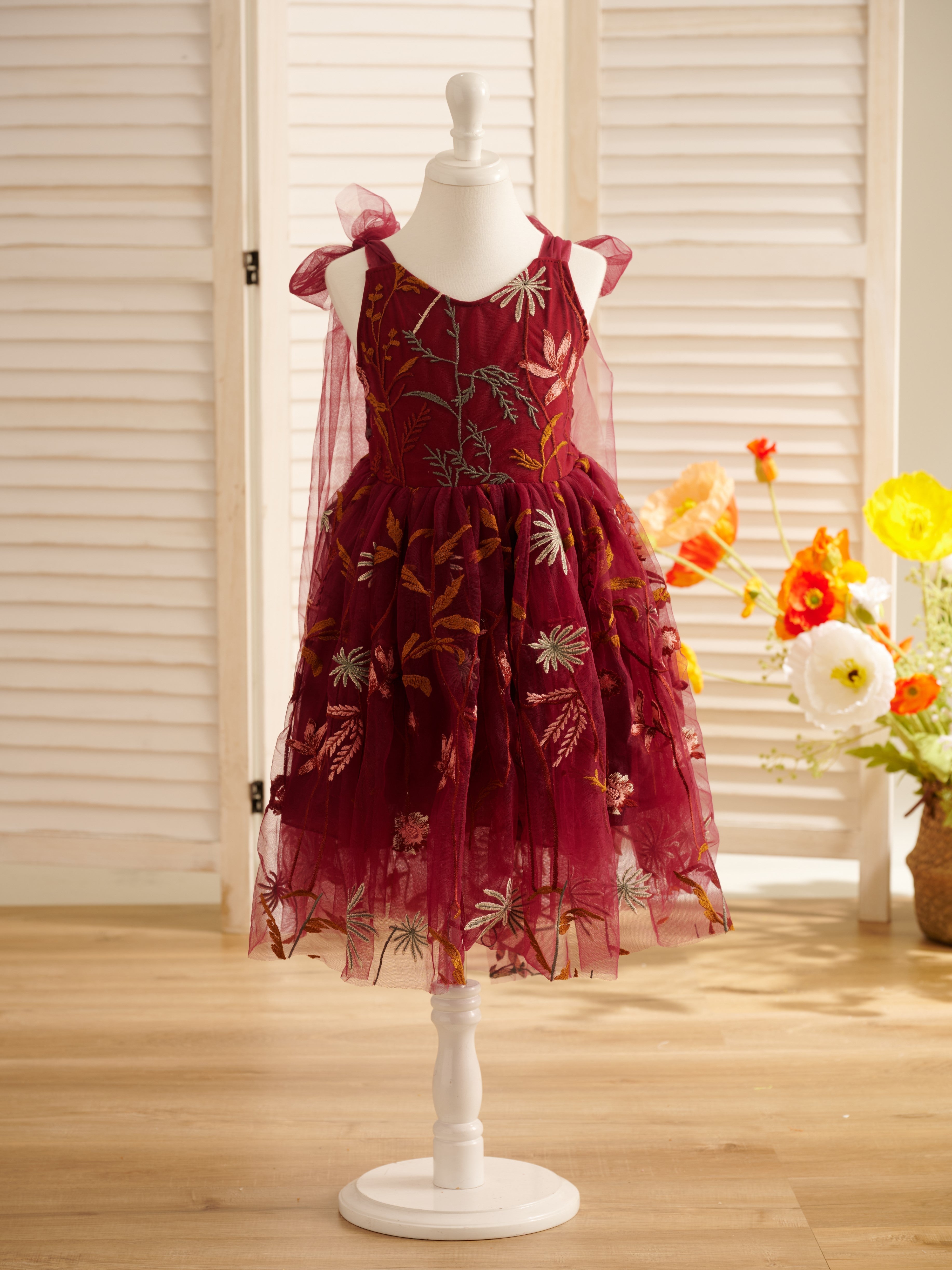Vestido de niña pequeña hasta la rodilla, de encaje y tul color naranja quemado con bordados. 