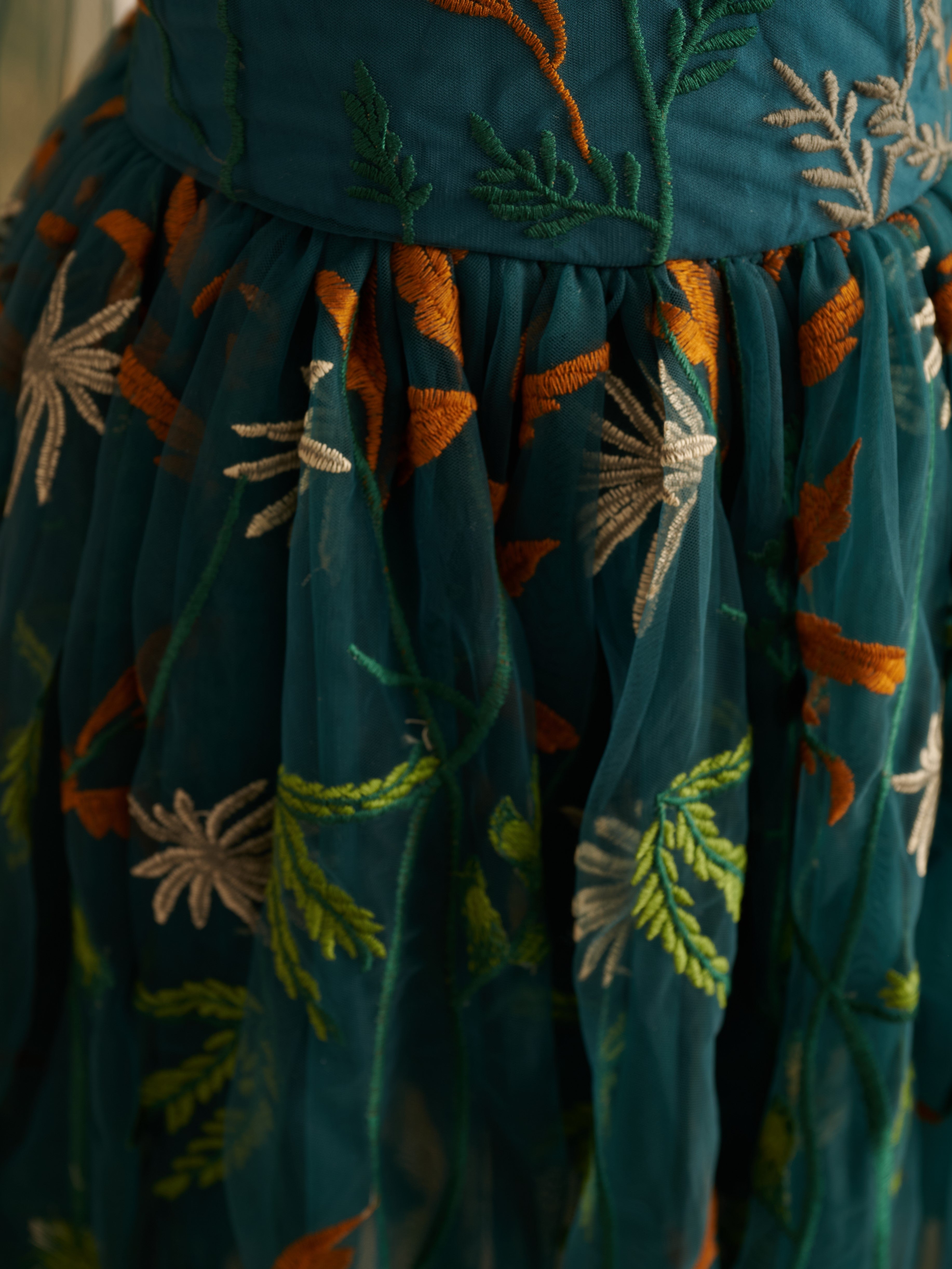 Vestido de niña pequeña hasta la rodilla, de encaje y tul color naranja quemado con bordados. 