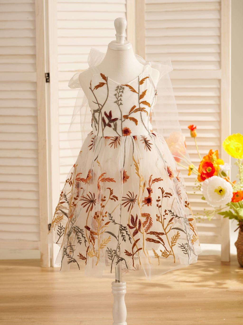 Vestido de niña pequeña hasta la rodilla, de encaje y tul color naranja quemado con bordados. 