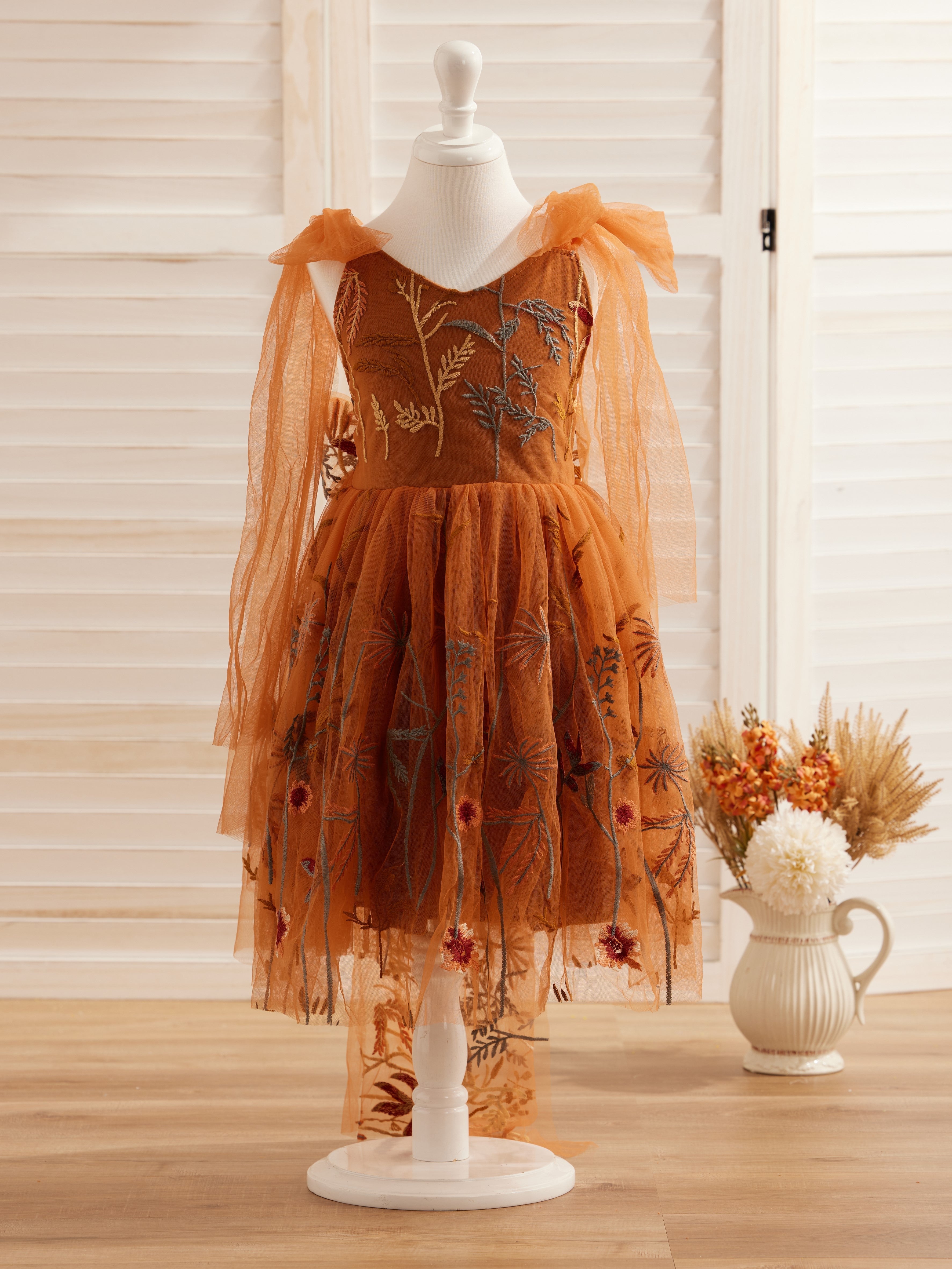 Vestido de niña pequeña hasta la rodilla, de encaje y tul color naranja quemado con bordados. 