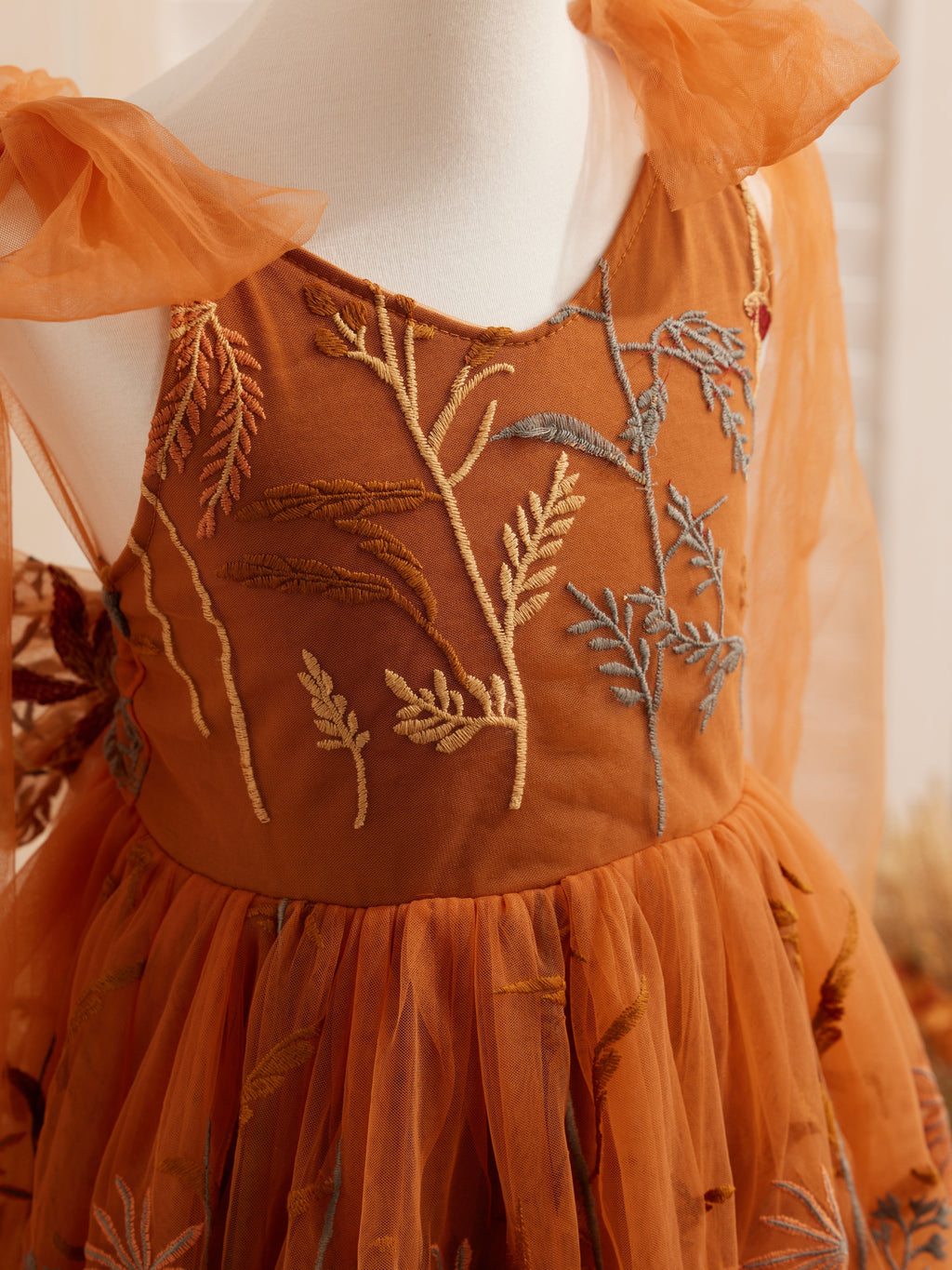 Vestido de niña pequeña hasta la rodilla, de encaje y tul color naranja quemado con bordados. 