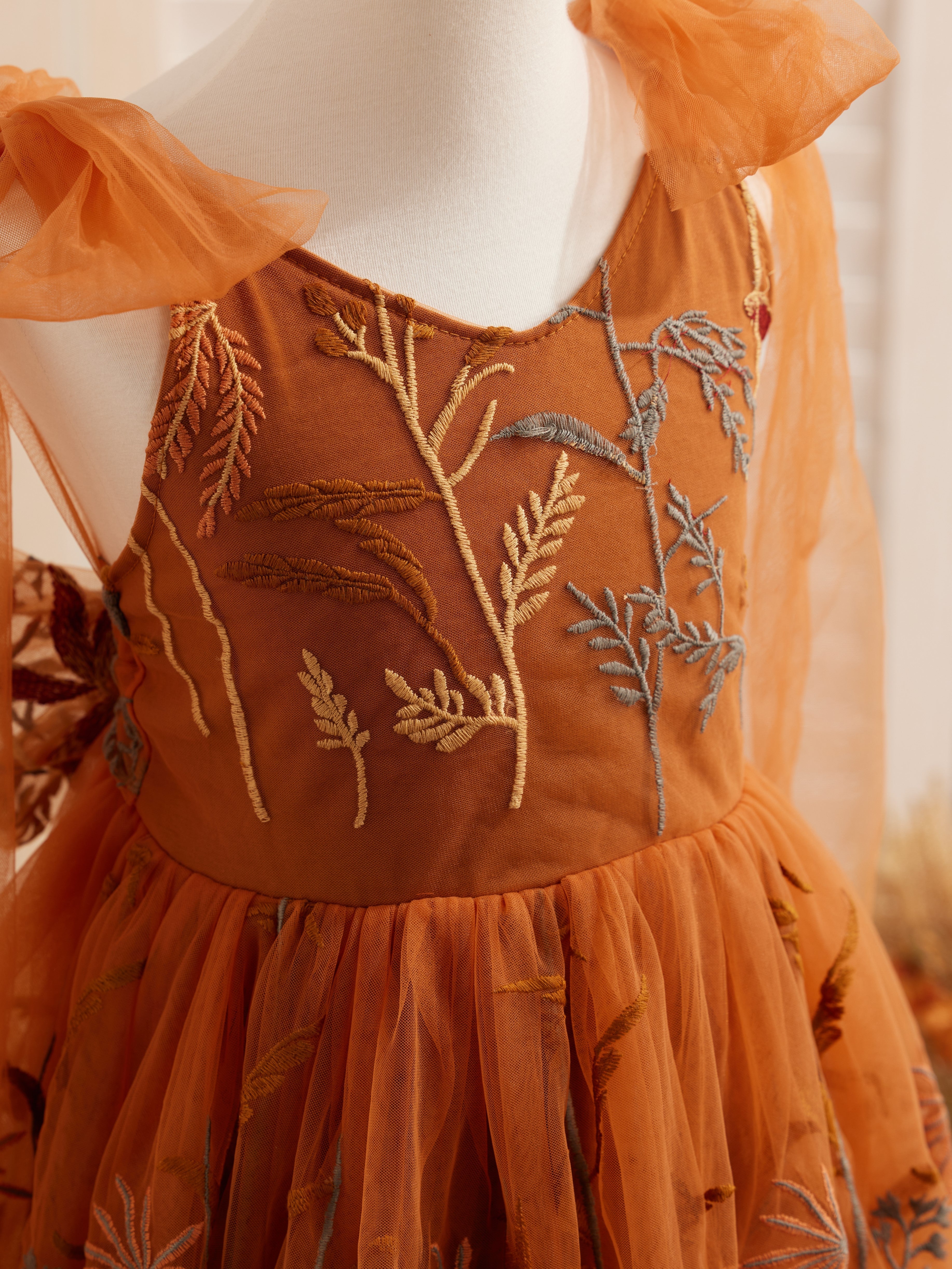 Vestido de niña pequeña hasta la rodilla, de encaje y tul color naranja quemado con bordados. 