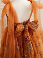 Vestido de niña pequeña hasta la rodilla, de encaje y tul color naranja quemado con bordados. 