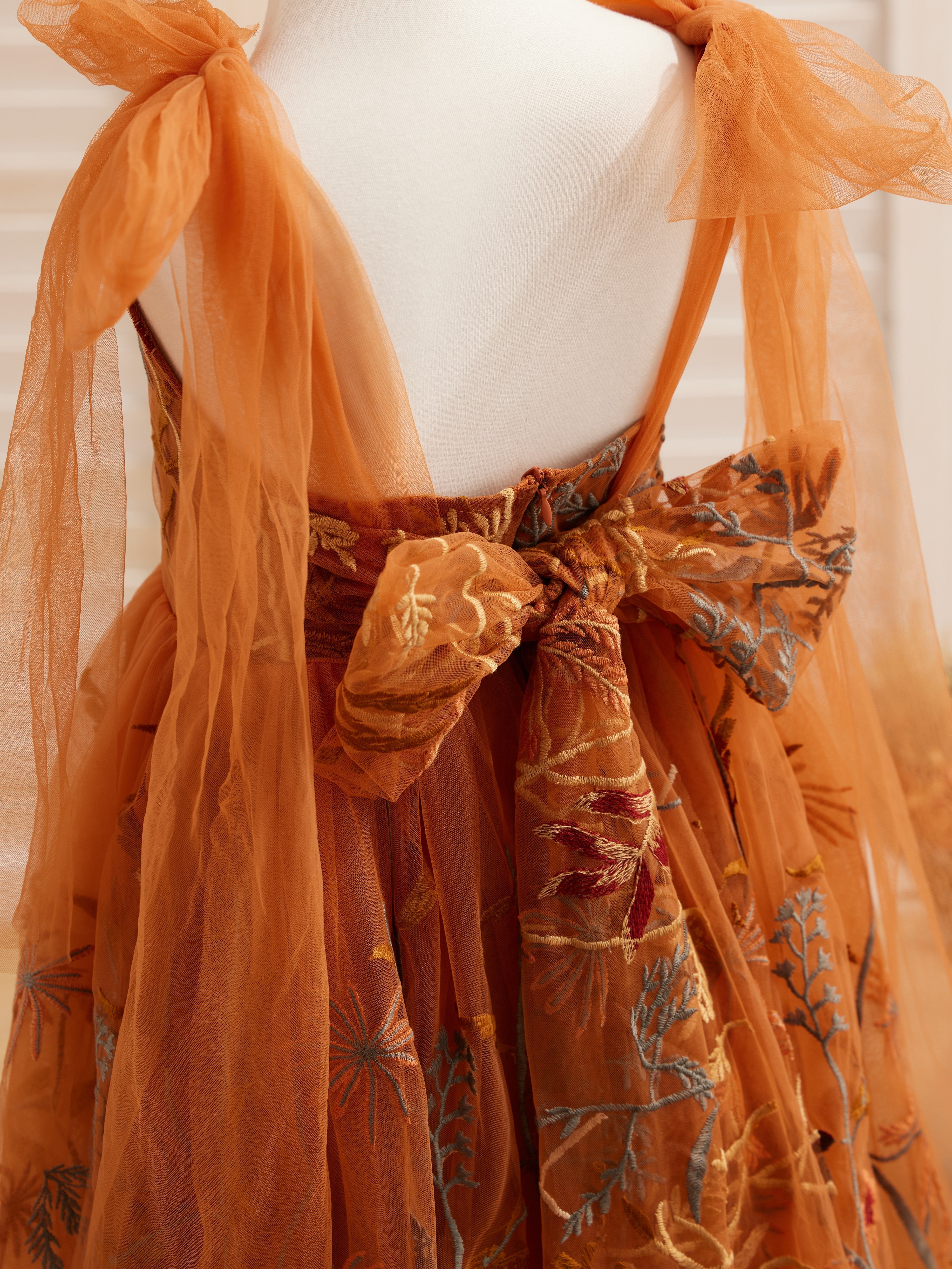Vestido de niña pequeña hasta la rodilla, de encaje y tul color naranja quemado con bordados. 