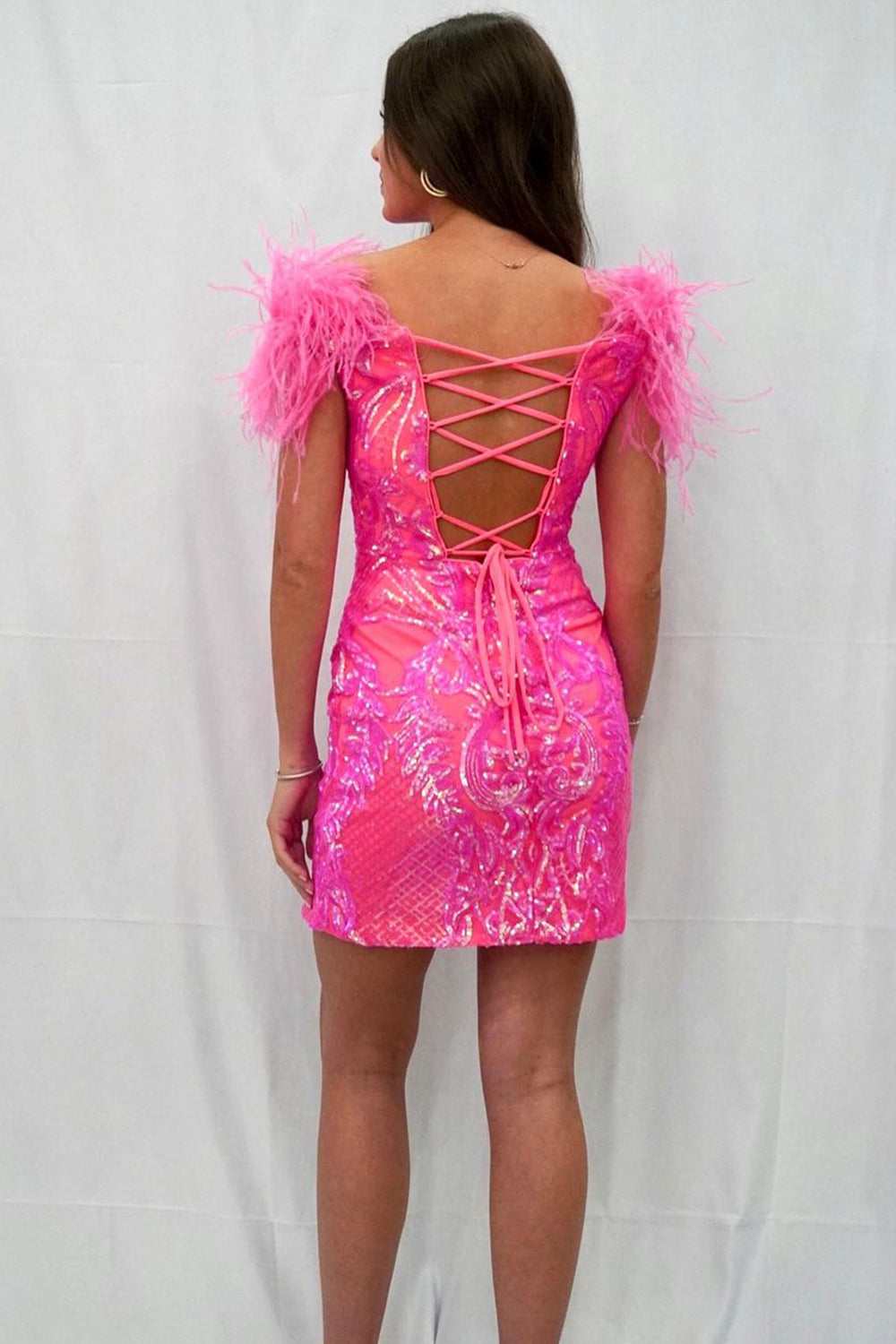 Vestido corto morado de fiesta, estilo tubo, con hombros descubiertos y detalles de plumas.