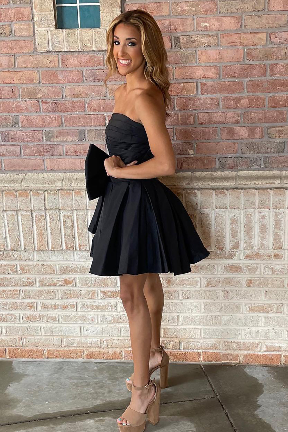 Vestido corto negro de corte recto y sin tirantes, ideal para fiestas de bienvenida, con lazo.
