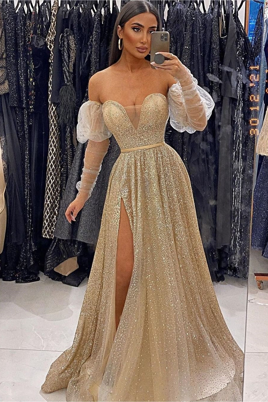 Robe de bal à manches longues et décolleté cœur, ornée de sequins et fendue.