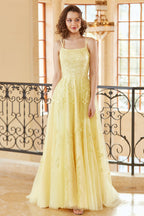 Magnifique robe de bal longue jaune à bretelles spaghetti et coupe trapèze, ornée d'appliqués.