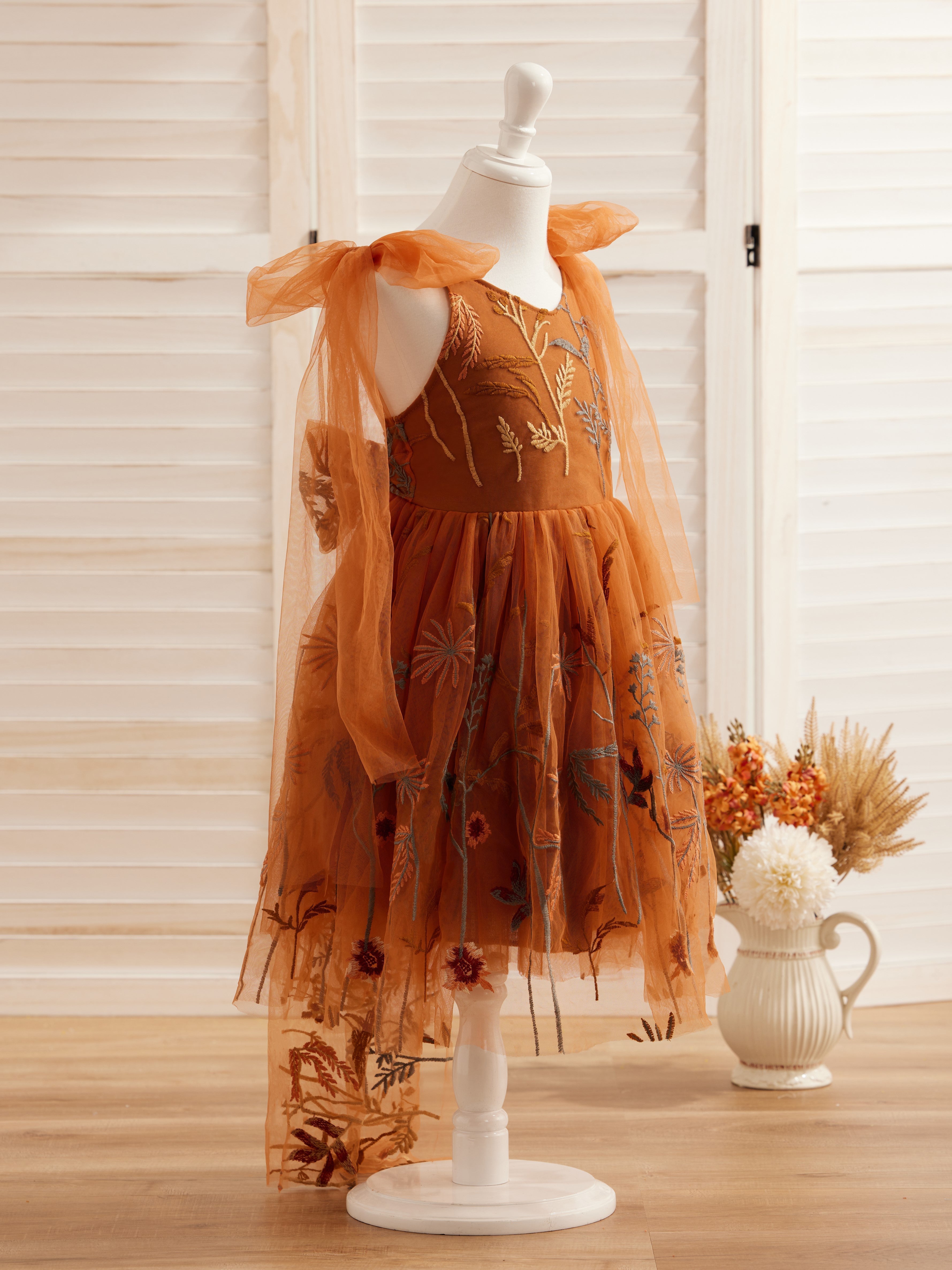 Vestido de niña pequeña hasta la rodilla, de encaje y tul color naranja quemado con bordados. 
