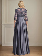 Robe de mariée longue en satin et dentelle, coupe trapèze, décolleté illusion, ornée d'un nœud à sequins. 