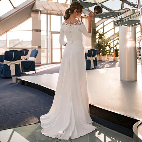 Robe de mariée civile simple en satin, manches 3/4 et col rond, coupe trapèze, ornée d'appliques en dentelle, disponible en 2025. Pas chère. 