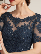 Robe de mariée longue en mousseline de soie et dentelle, coupe trapèze, décolleté illusion, ornée de sequins et de perles.