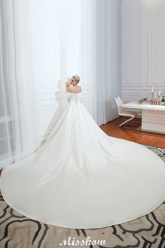 Vestido de novia blanco de corte princesa, manga tres cuartos, hombros descubiertos y línea A.