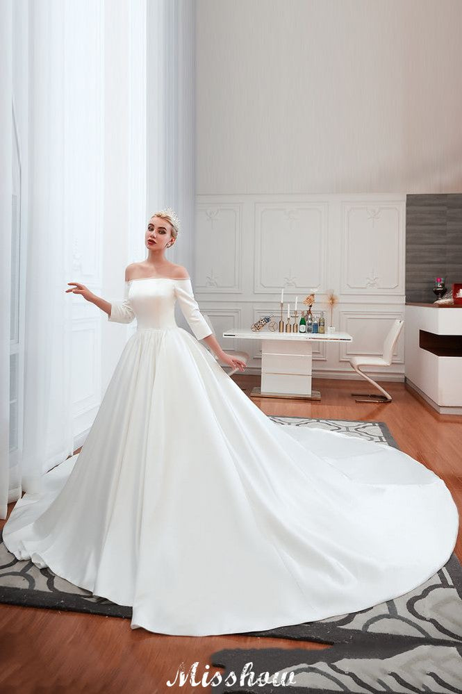 Vestido de novia blanco de corte princesa, manga tres cuartos, hombros descubiertos y línea A.