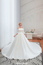 Vestido de novia blanco de corte princesa, manga tres cuartos, hombros descubiertos y línea A.