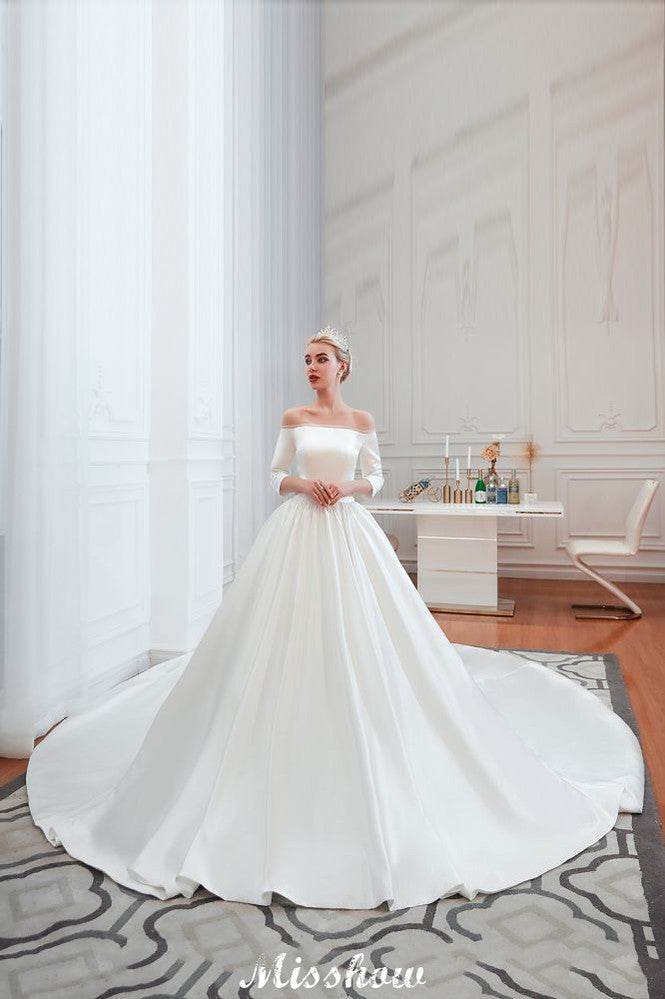 Vestido de novia blanco de corte princesa, manga tres cuartos, hombros descubiertos y línea A.