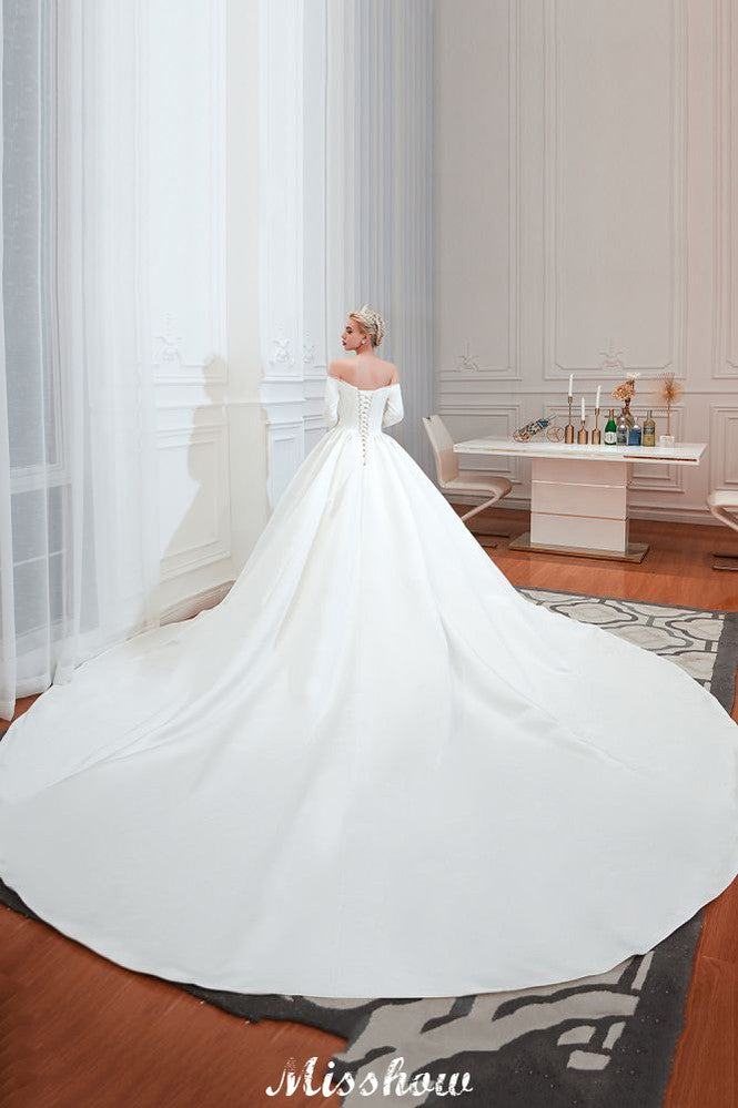 Vestido de novia blanco de corte princesa, manga tres cuartos, hombros descubiertos y línea A.