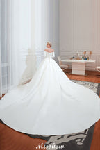 Vestido de novia blanco de corte princesa, manga tres cuartos, hombros descubiertos y línea A.