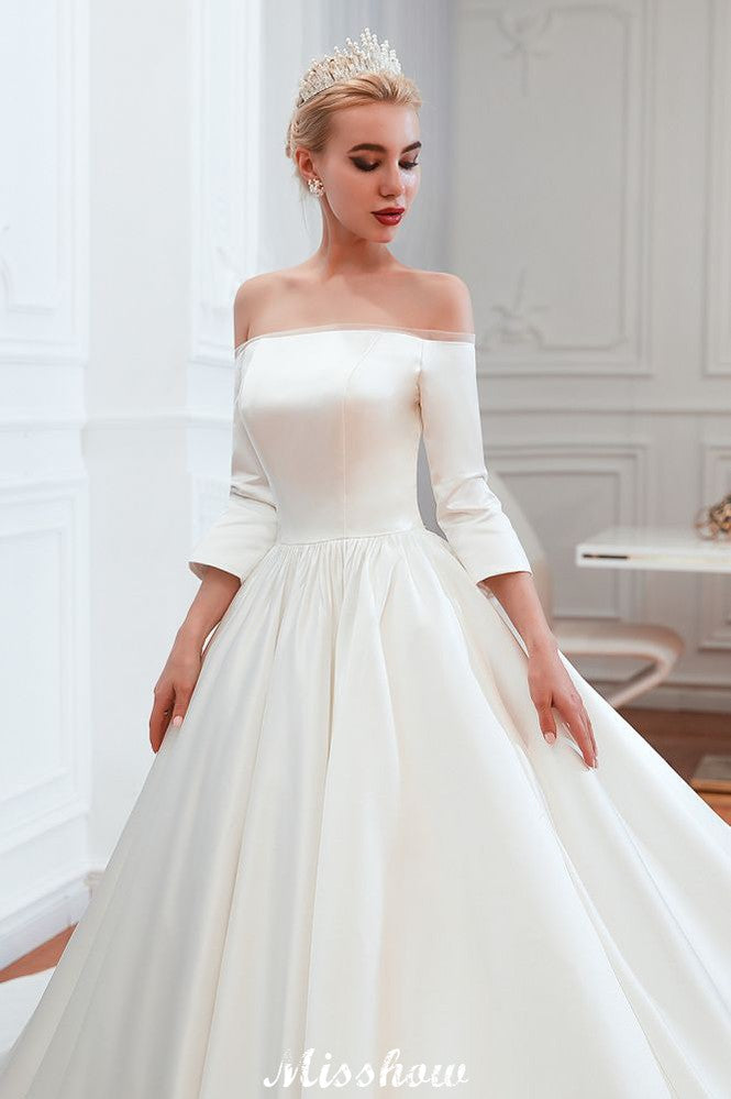 Vestido de novia blanco de corte princesa, manga tres cuartos, hombros descubiertos y línea A.