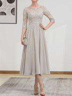 Robe de mariée trapèze en mousseline de soie et dentelle, longueur thé, ornée de perles et de sequins, avec décolleté en A et effet illusion.