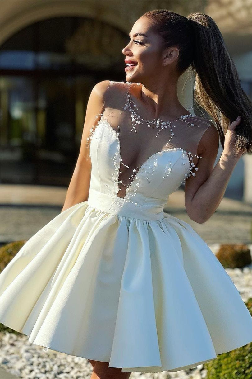 Vestido corto de fiesta color marfil, corte en A, escote ilusión y cuentas