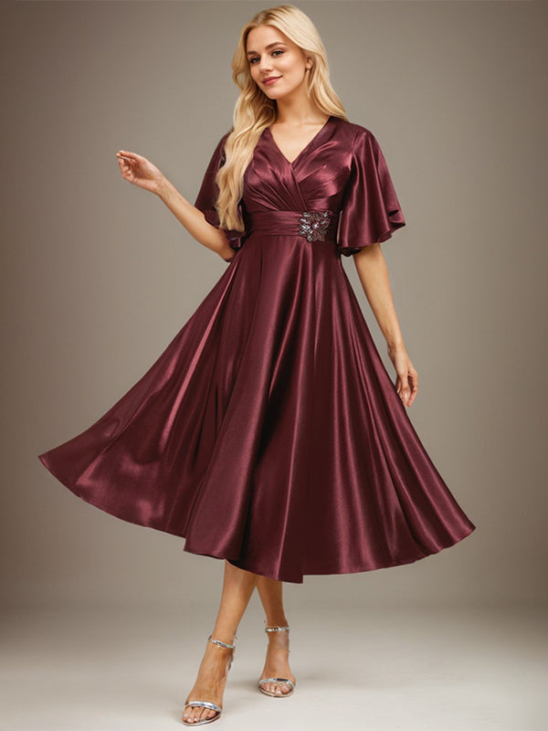 Vestido de novia de satén elástico, corte en A, escote en V, largo hasta la rodilla, con cuentas y pliegues. 