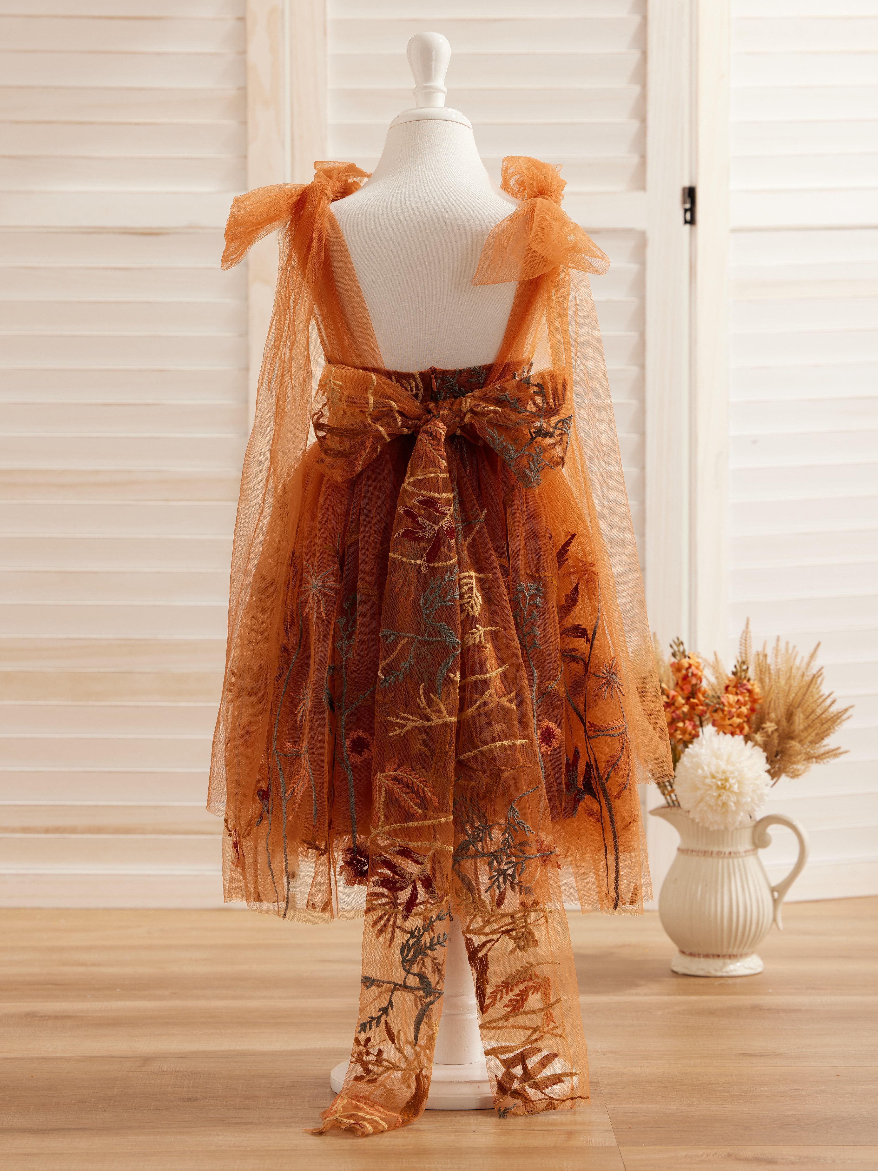 Vestido de niña pequeña hasta la rodilla, de encaje y tul color naranja quemado con bordados. 
